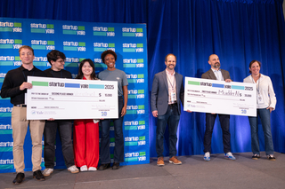 Startup Yale winners pose with giant checks on stage